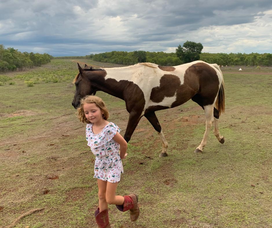 girl walking in field with horse